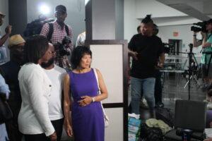 Mayor Olivia Chow standing beside Pastor Judith looking at the refugee living area in Revivaltimes Tabernacle Church with a crowd behind them