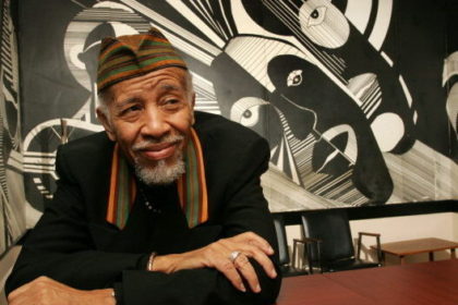 Charles Roach sitting with arms crossed on a table.