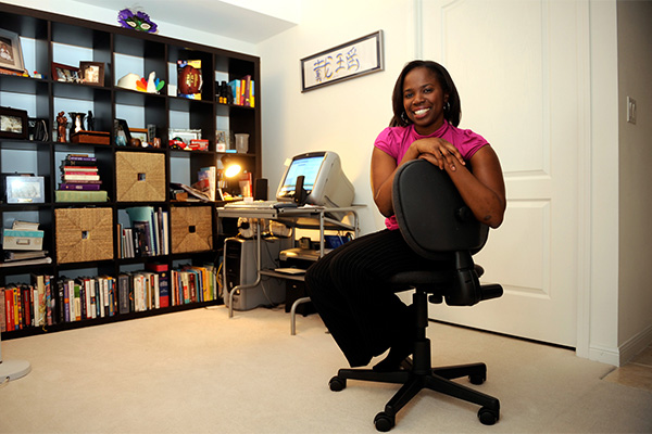 Dayo Kefentse poses on a swivel chair in a home office space.