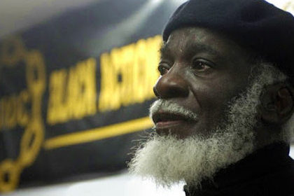 Dudley Laws in front of a Black Action Defence Committee banner.