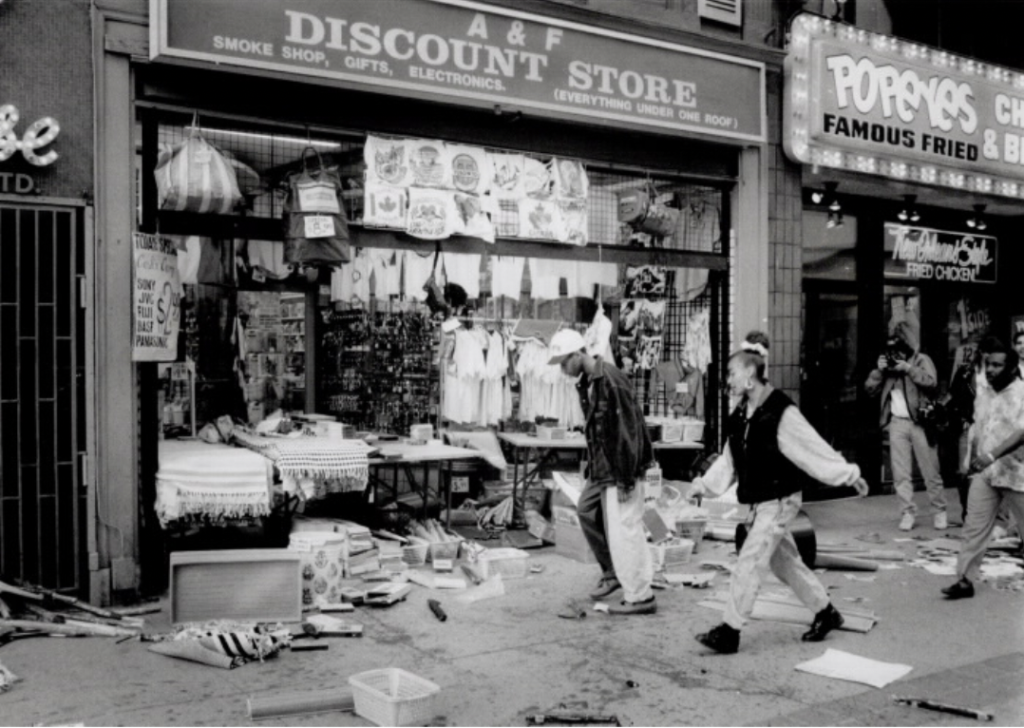 Protesters walking past damaged store fronts on Yonge Street during the Yonge Street Uprising in 1992.